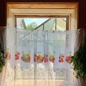 Lace curtains hanging in a wooden window frame with plants on either side